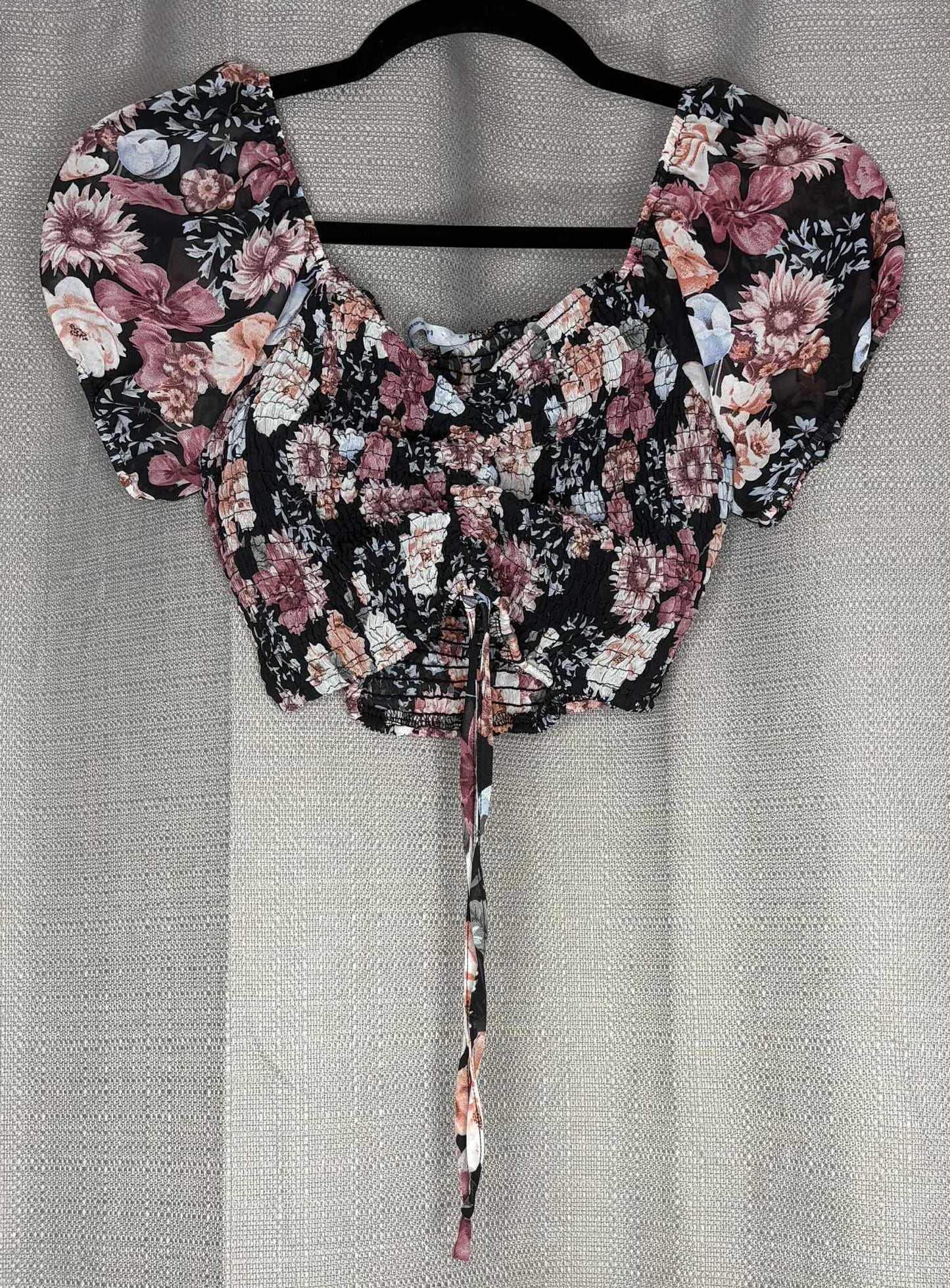 Floral blouse with puff sleeves on a hanger against a neutral background
