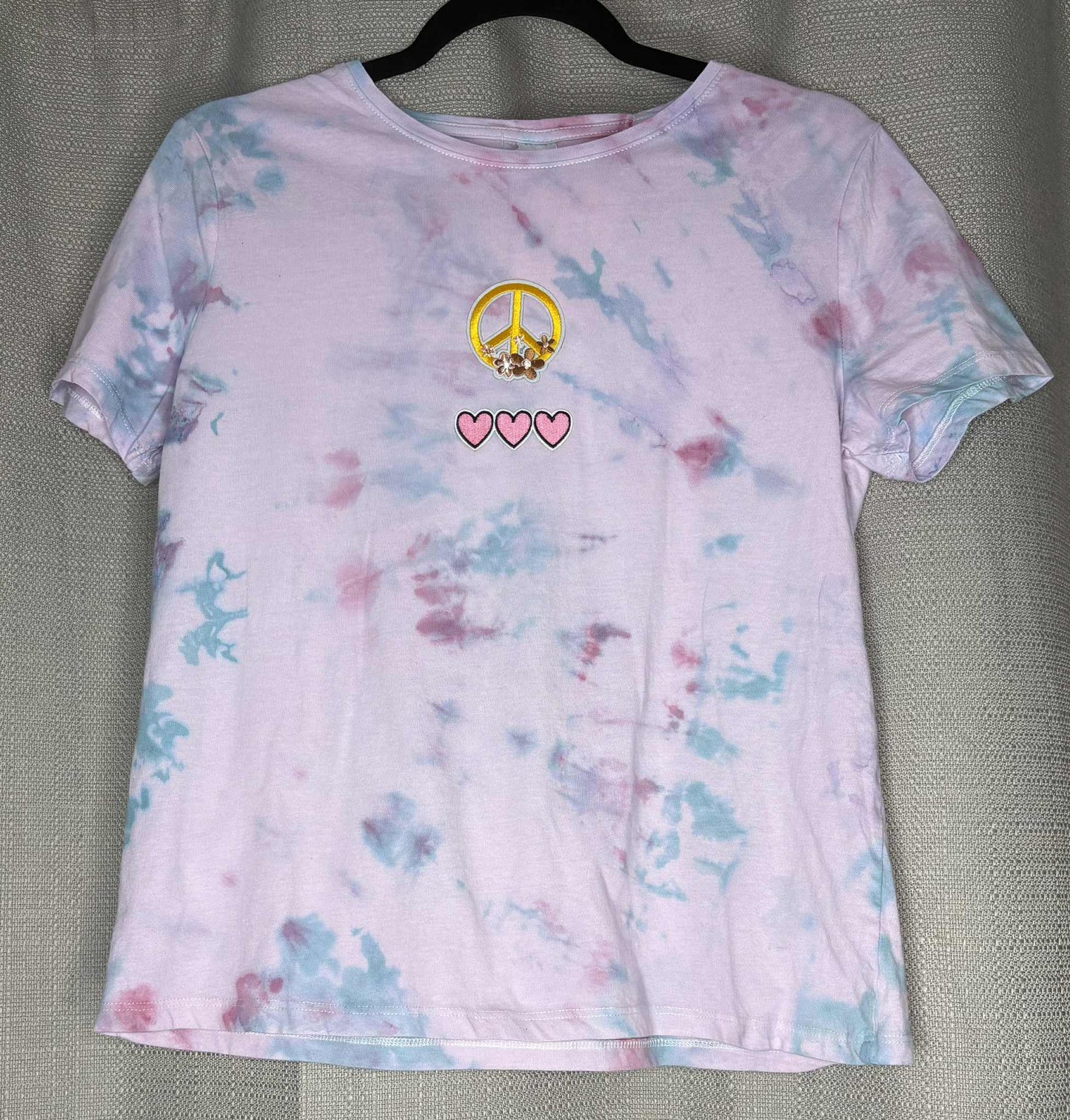 Tie-dye t-shirt with peace symbol and hearts on a gray background