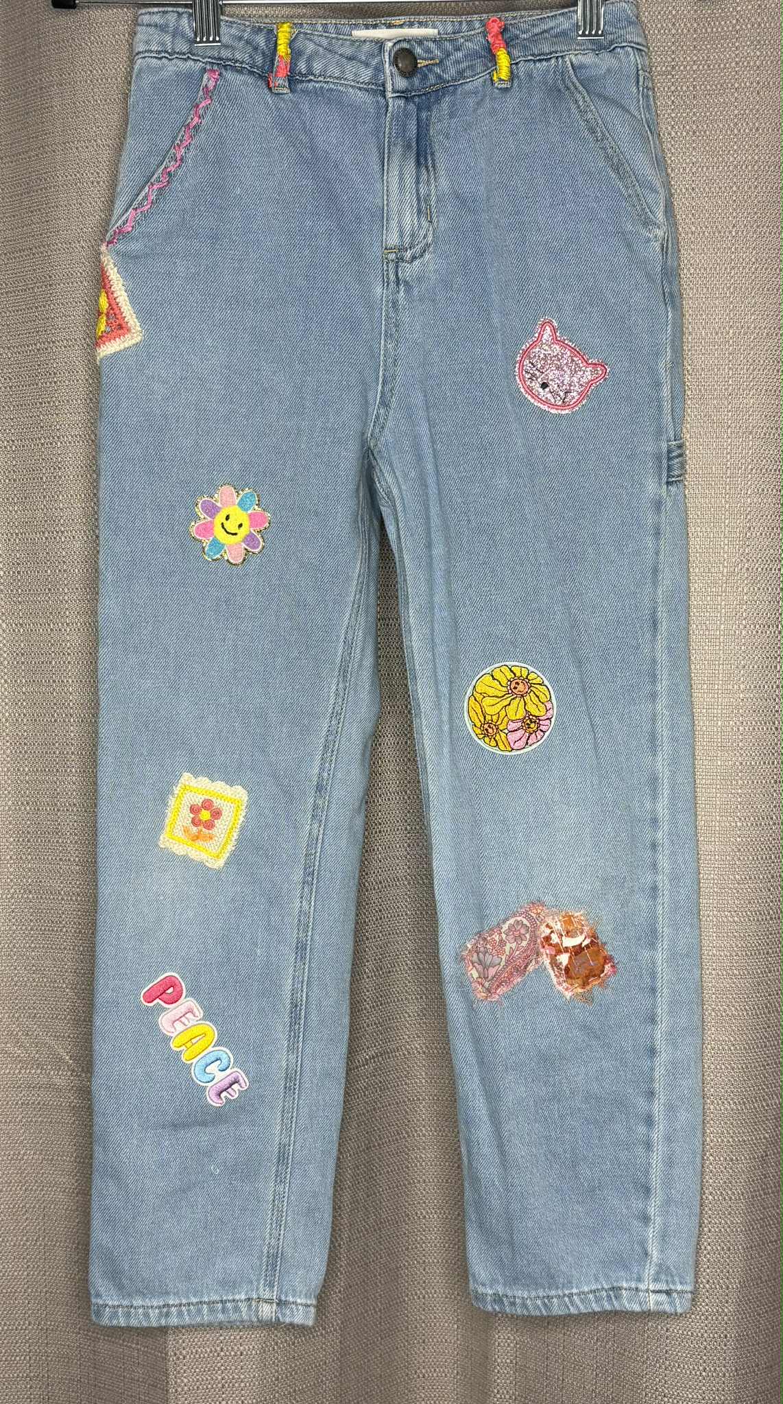 Light blue jeans with colorful patches on a light denim background