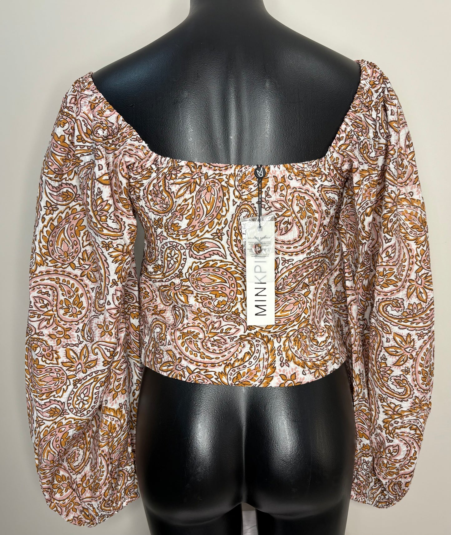 Patterned blouse on a mannequin with a visible brand tag against a plain background