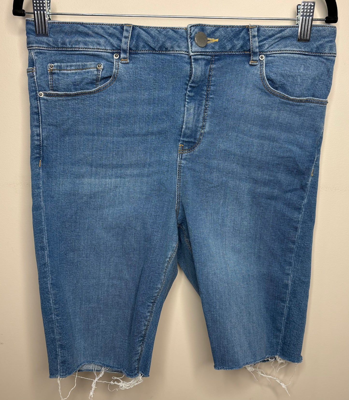 Blue denim shorts with frayed hems on a beige background