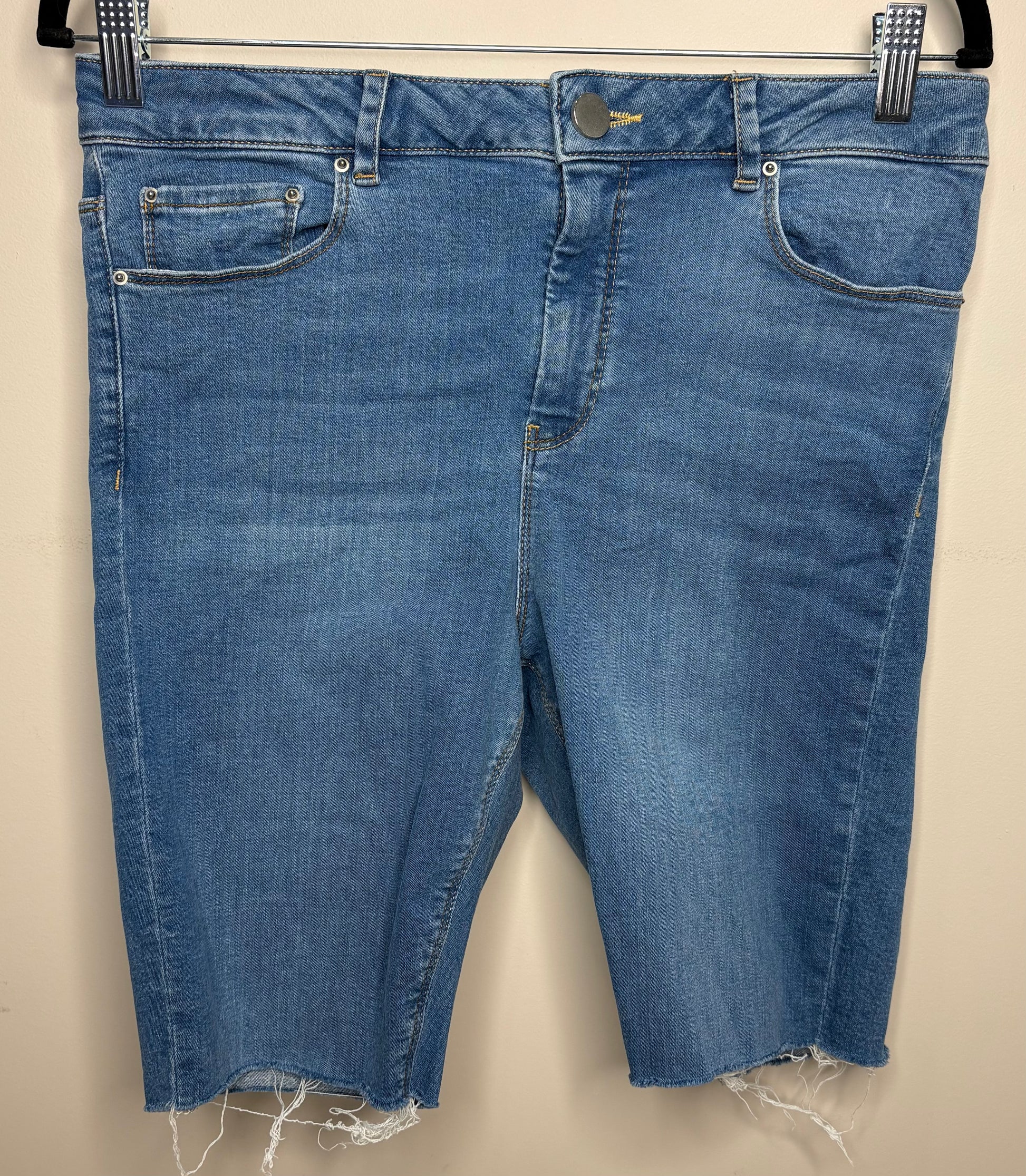 Blue denim shorts with frayed hems on a beige background