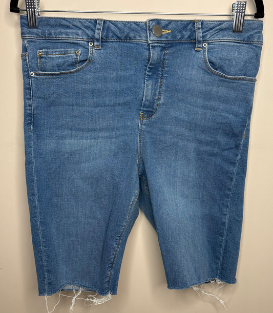 Blue denim shorts with frayed hems on a beige background