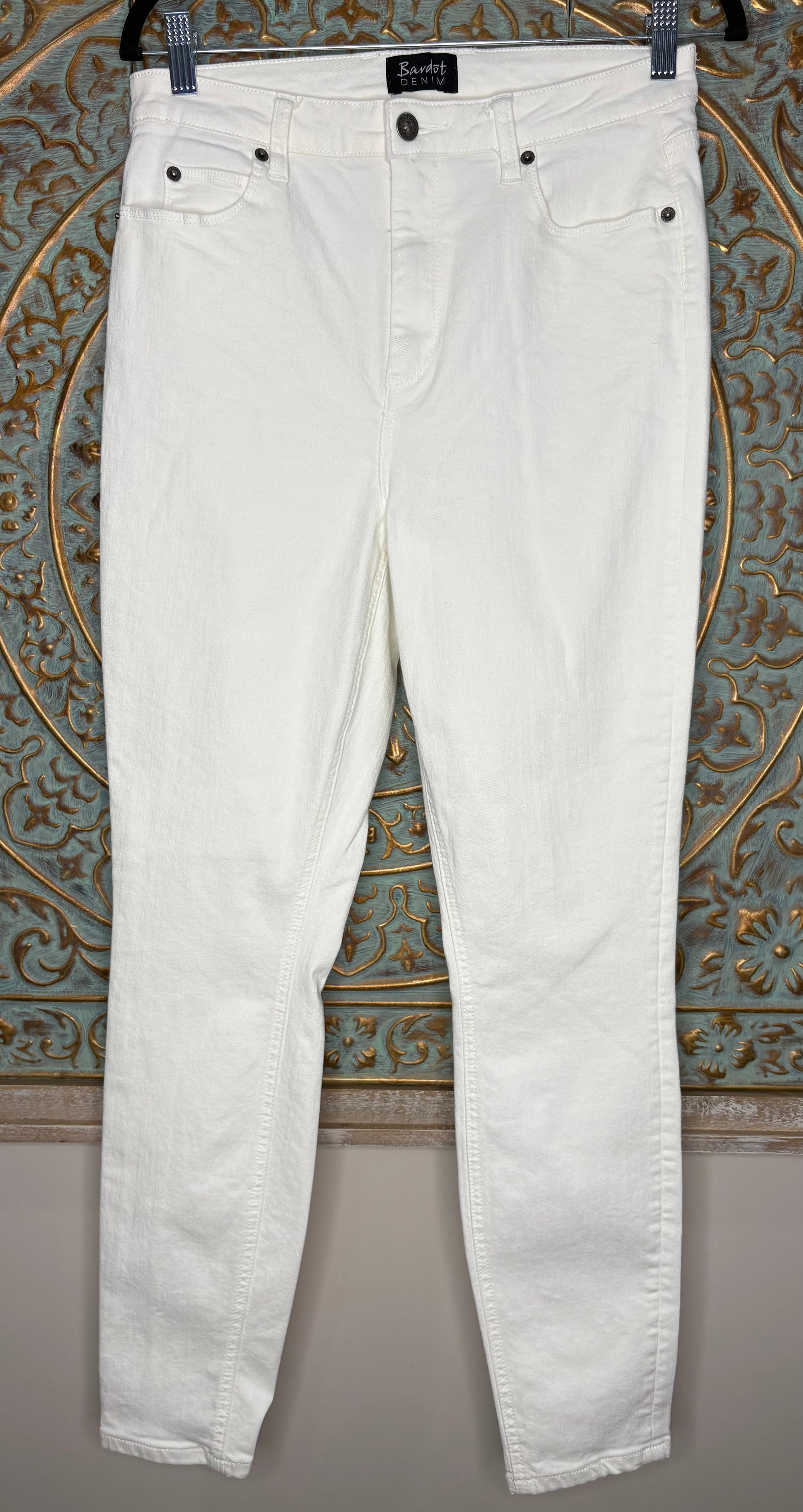 White jeans hanging against a decorative wall.