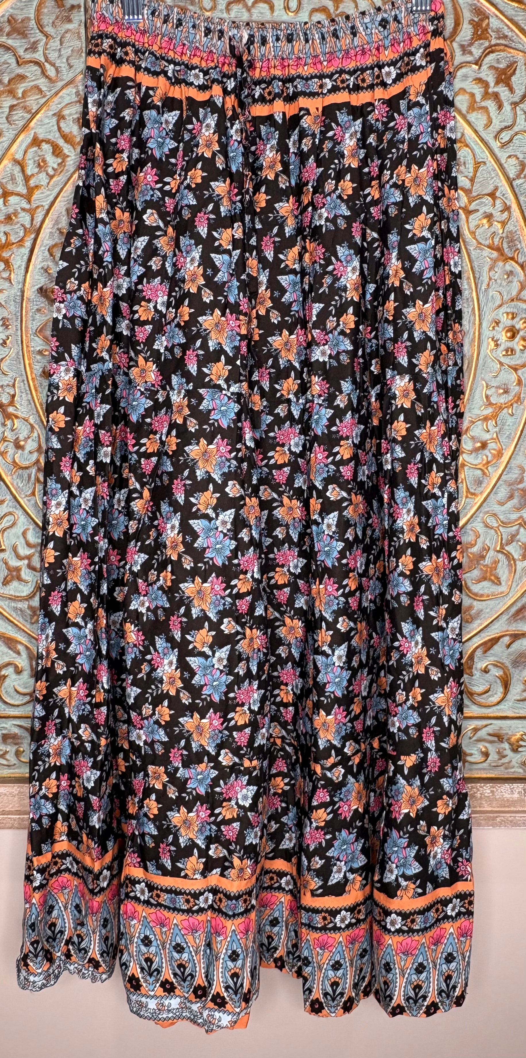 Floral patterned skirt with colorful border on a decorative wall background