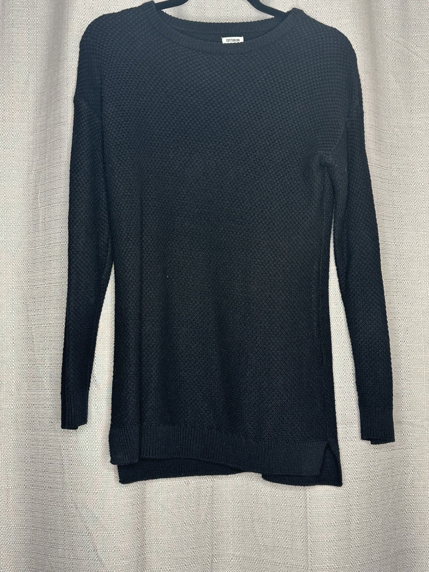 Black textured sweater on a light gray background