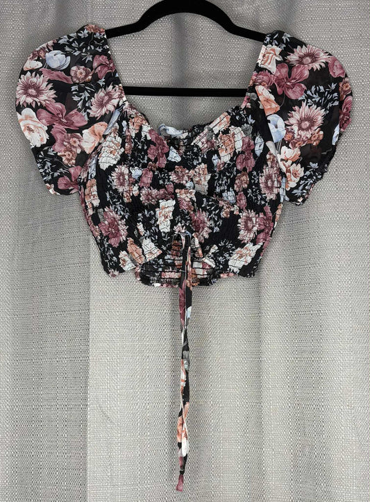 Floral blouse with puff sleeves on a hanger against a neutral background

