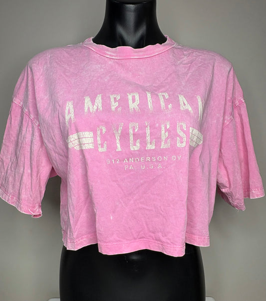 Pink t-shirt with 'American Cycles' text on a mannequin against a gray background