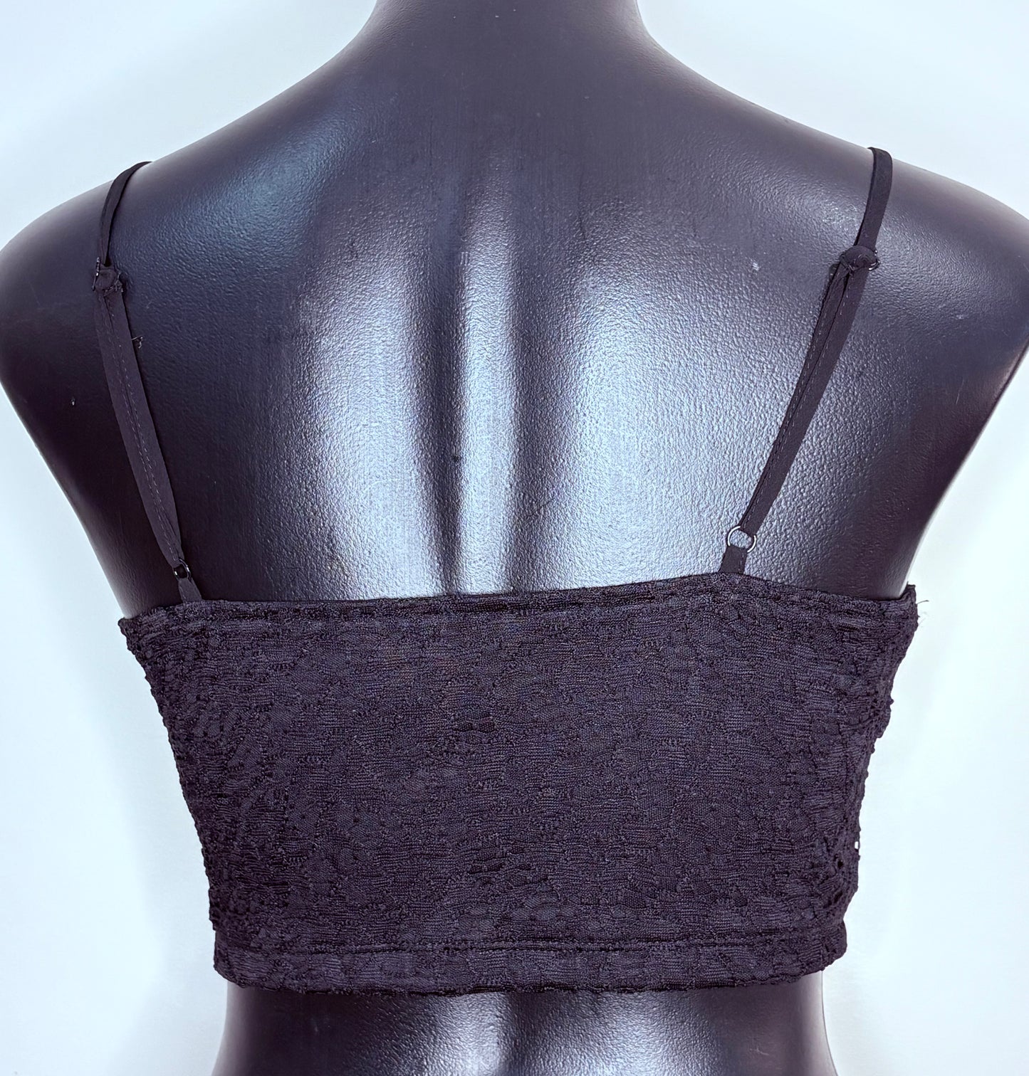 Black lace bralette on a mannequin against a light blue background