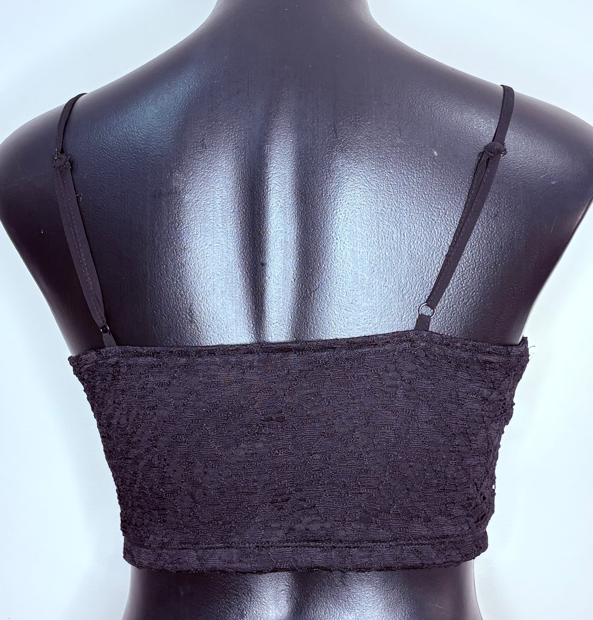 Black lace bralette on a mannequin against a light blue background