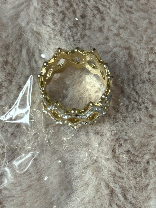 Gold ring with intricate design on a textured surface