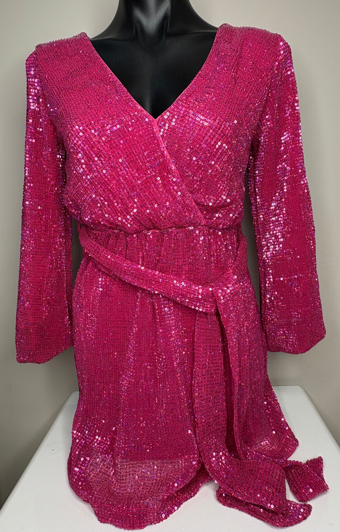 Pink sequin dress on a mannequin against a neutral background