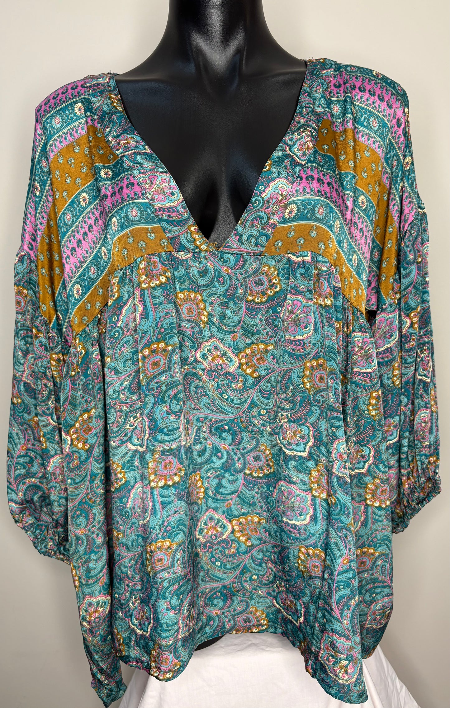 Colorful patterned blouse on a mannequin against a white background