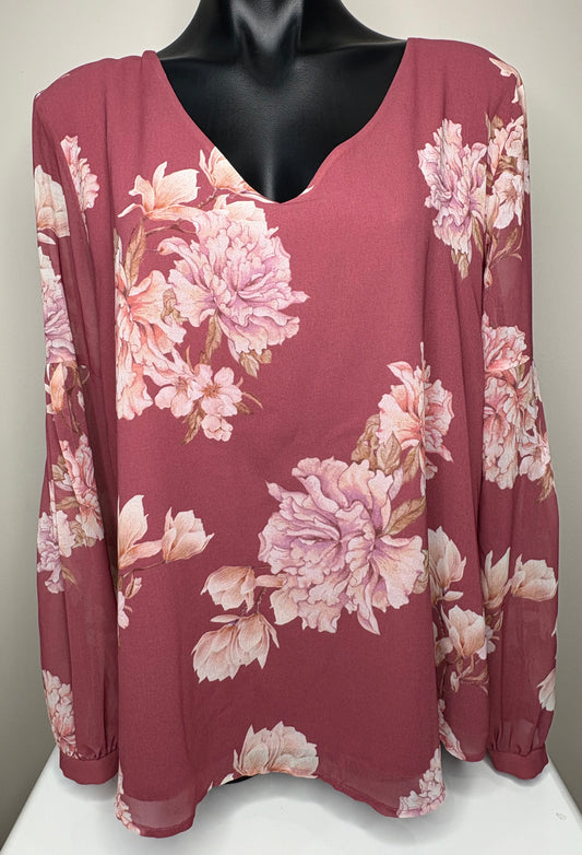 Floral blouse with pink and white flowers on a mannequin against a neutral background