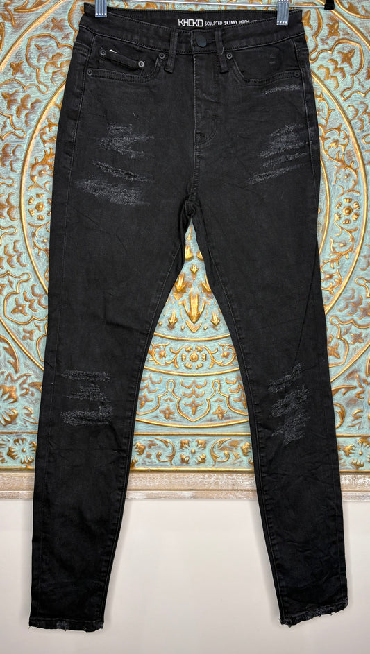 Black distressed jeans hanging against a decorative wall.