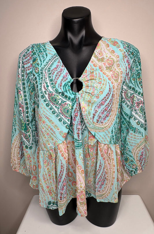 Colorful patterned top on a mannequin against a neutral background