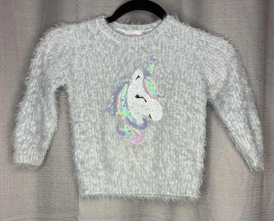 Gray sweater with a colorful unicorn design on a hanger against a gray background