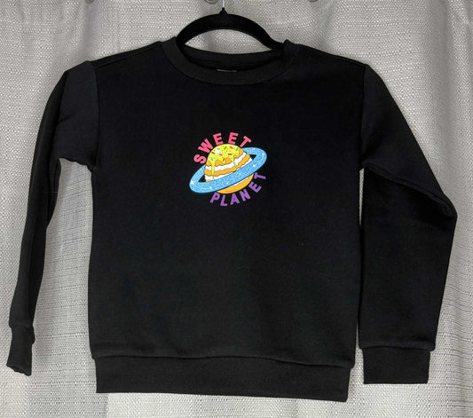 Black sweatshirt with 'Sweet Planet' graphic on a hanger against a neutral background