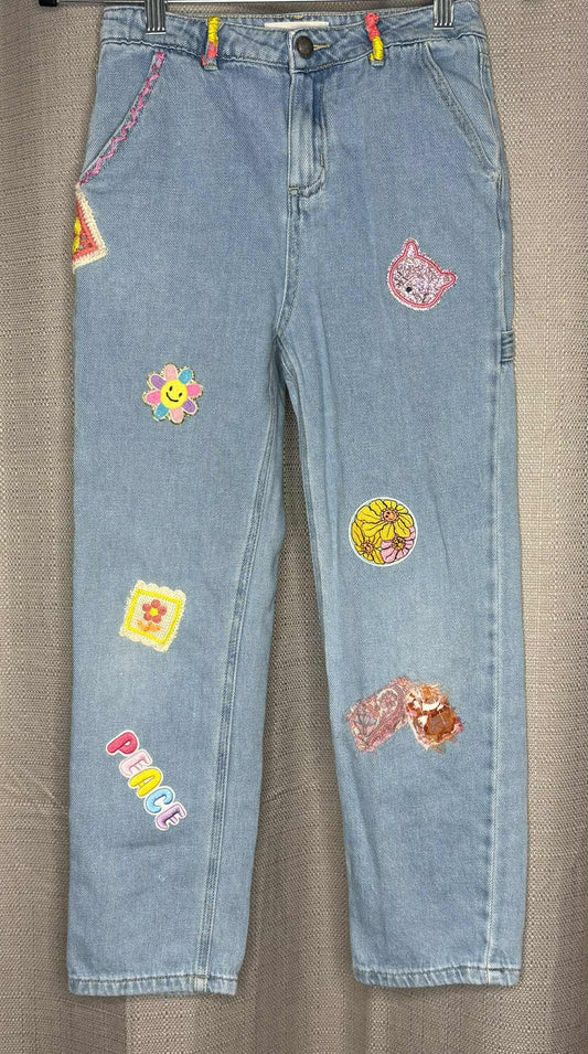Light blue jeans with colorful patches on a  light denim background