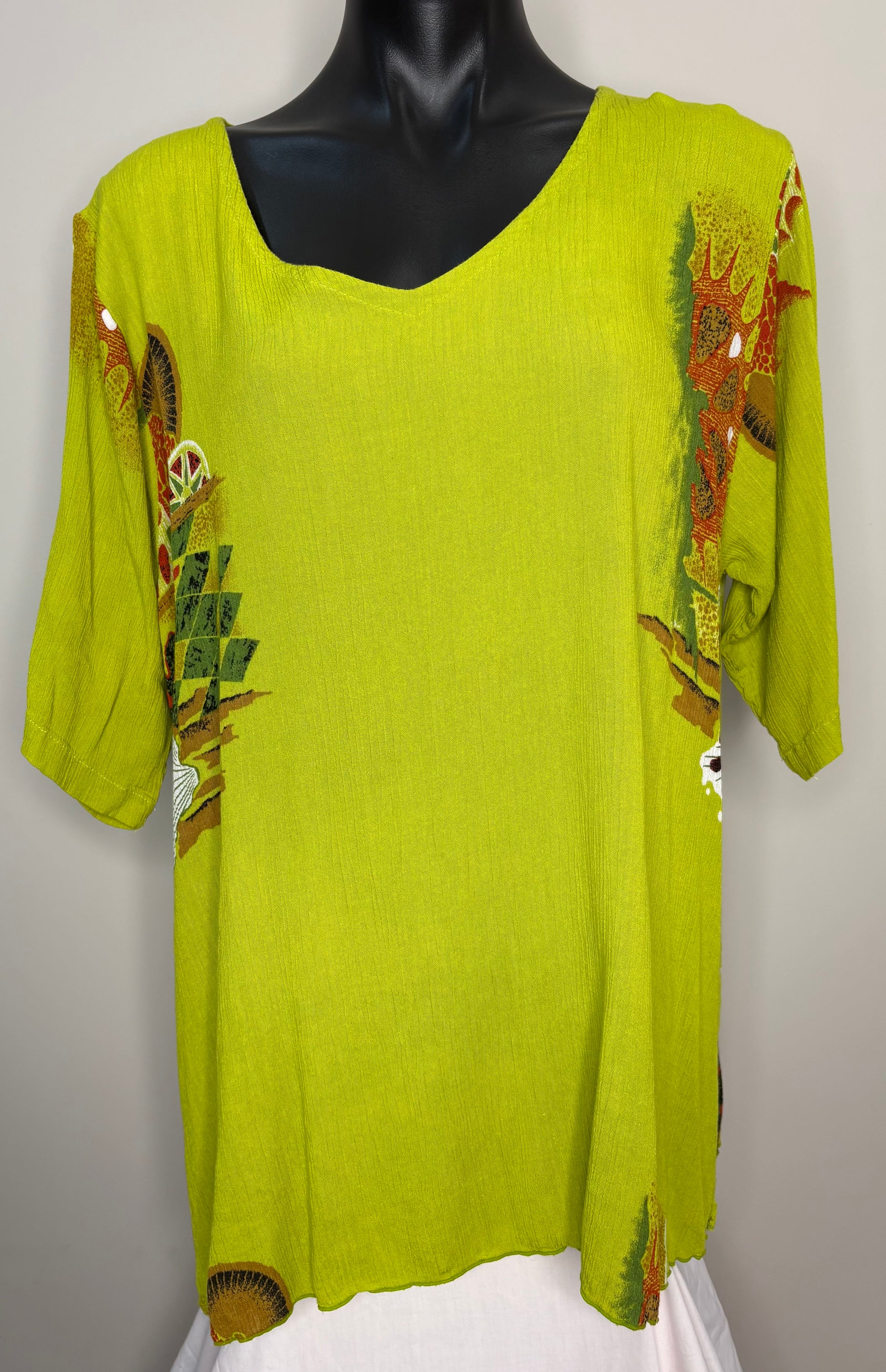 Green top with floral embroidery on a mannequin against a white background
