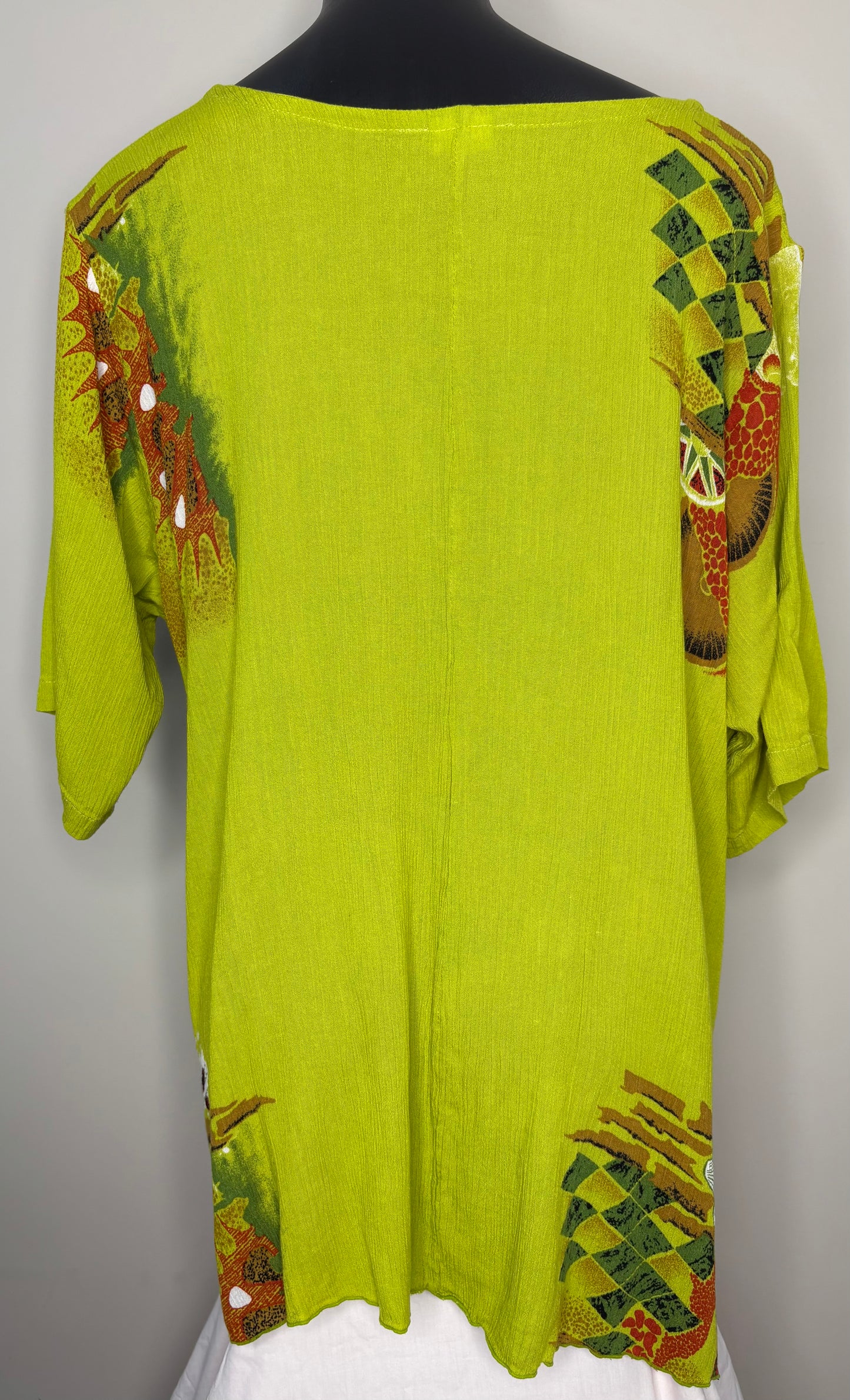Green dress with colorful patterns on a mannequin against a gray background
