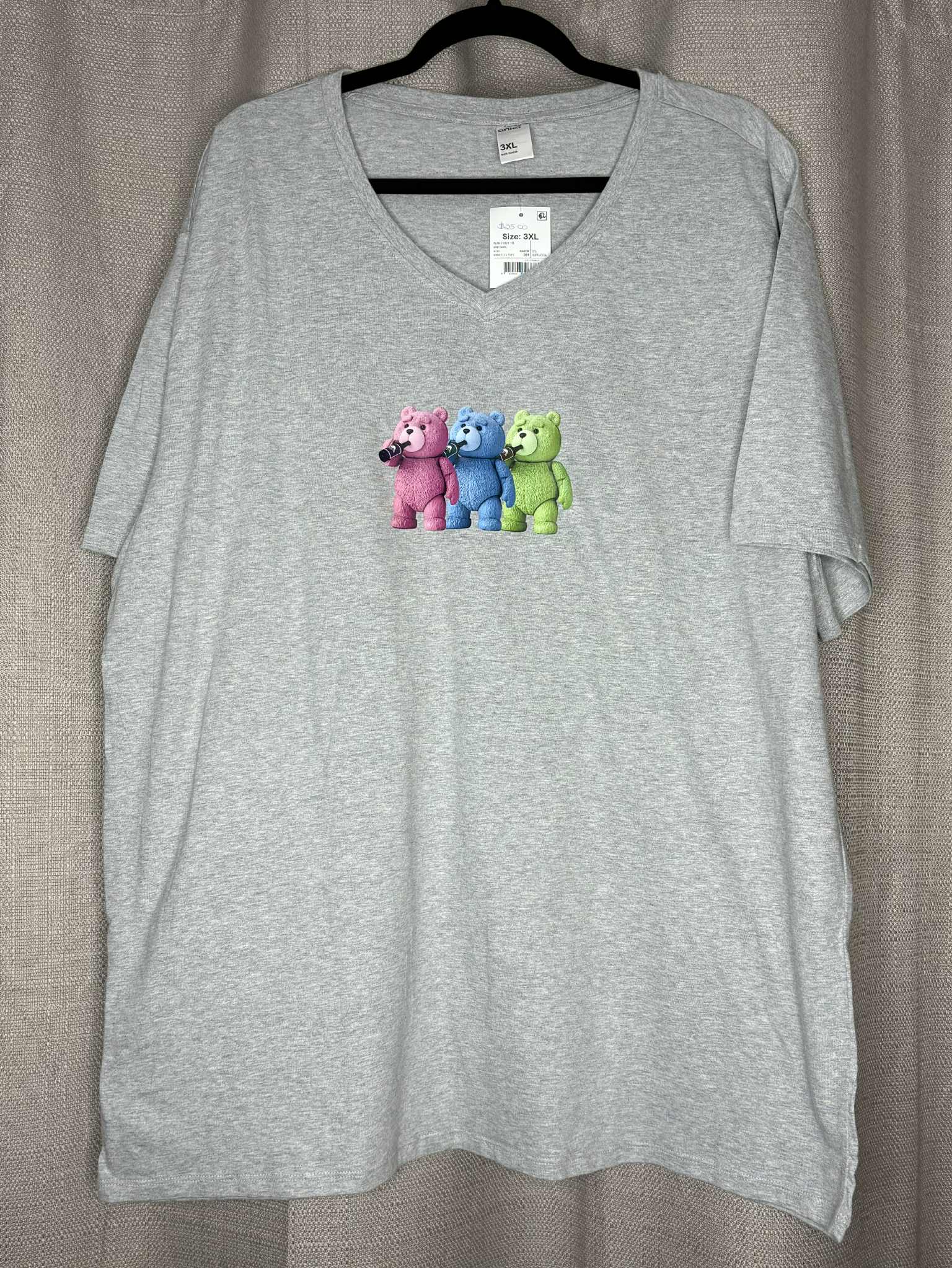 Gray t-shirt with colorful bear design on a hanger against a neutral background