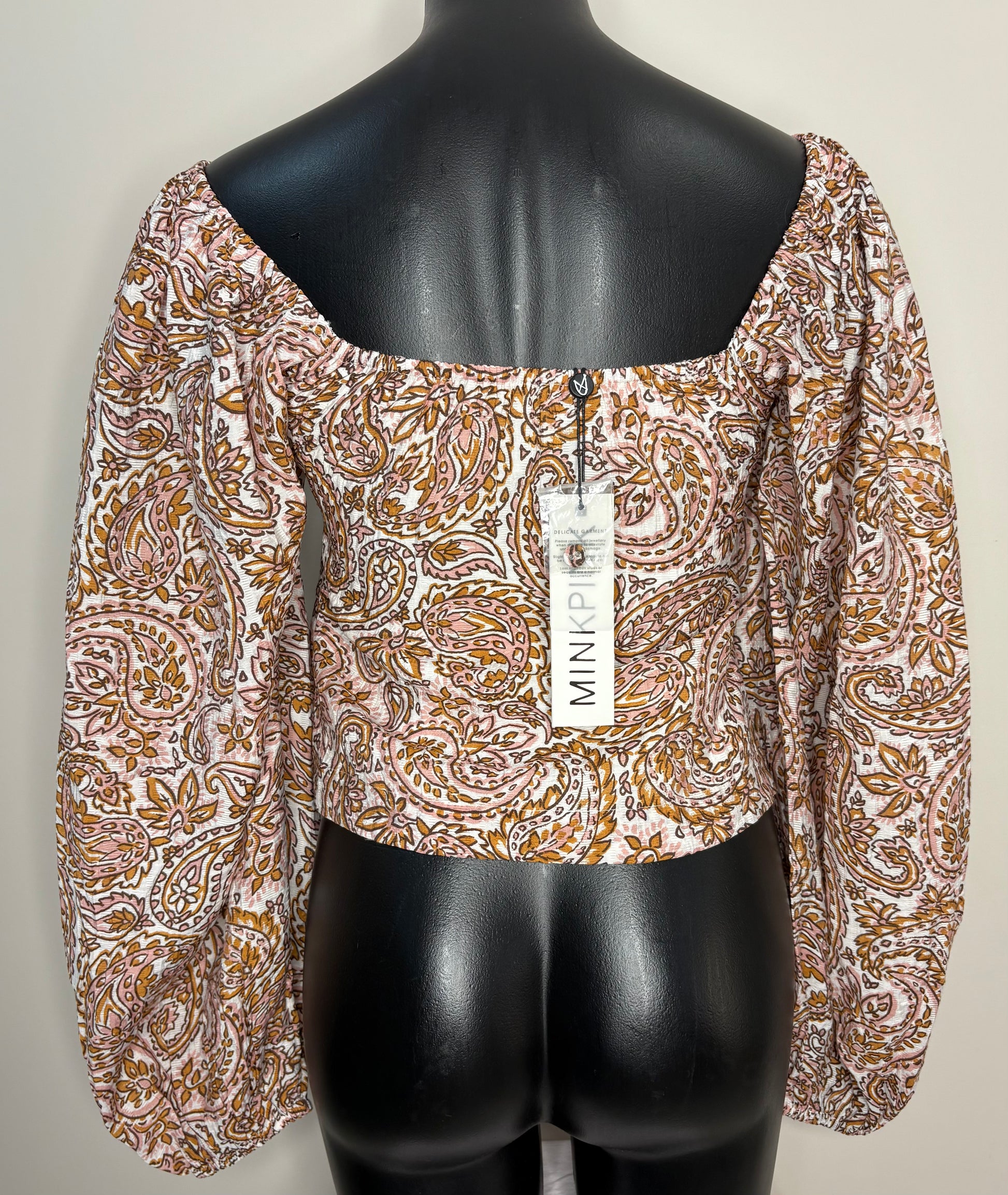 Patterned blouse on a mannequin with a visible brand tag against a plain background
