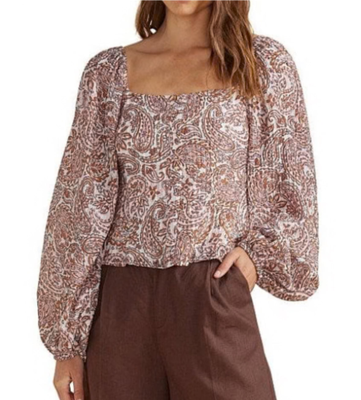 Woman wearing a patterned blouse and brown pants on a white background