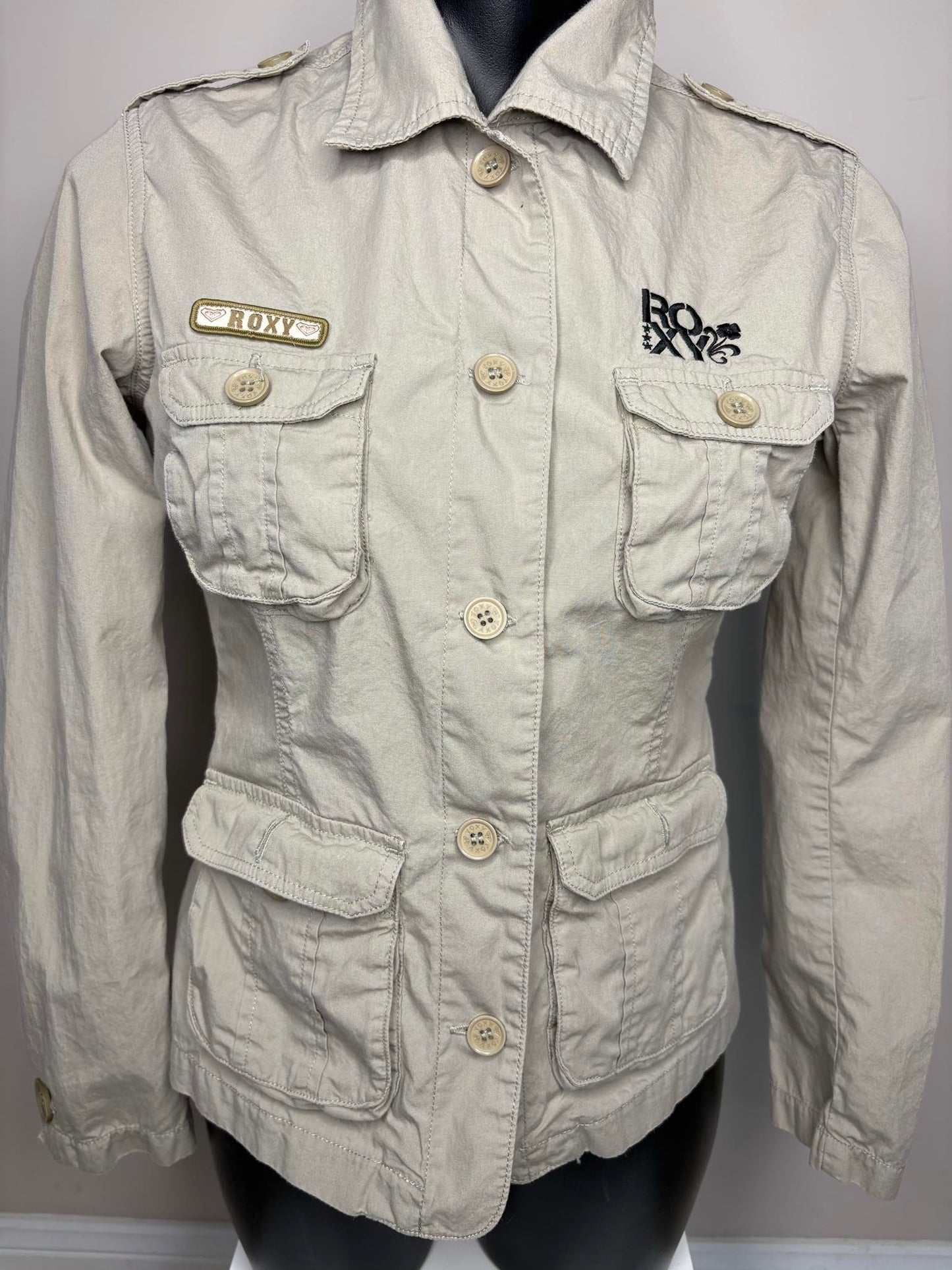 Light beige jacket with brand logos on a mannequin against a gray background