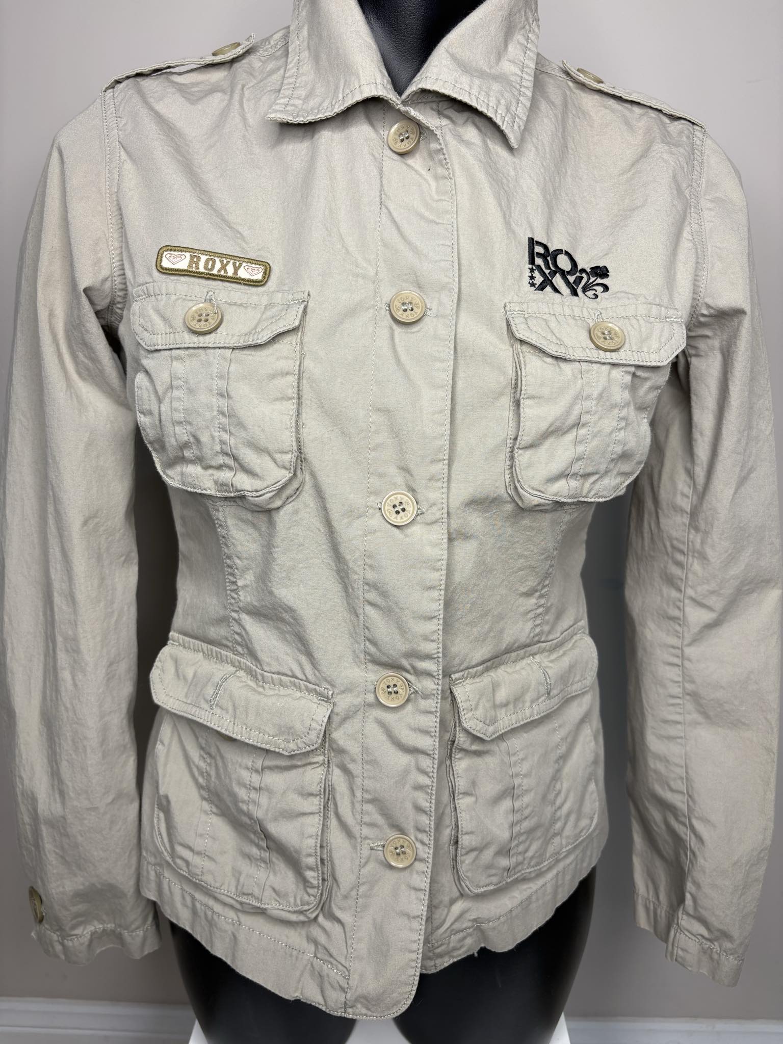 Light beige jacket with brand logos on a mannequin against a gray background