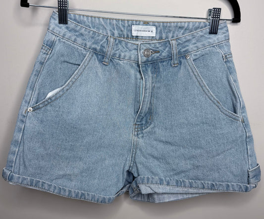 Pair of blue denim shorts on a hanger against a gray background