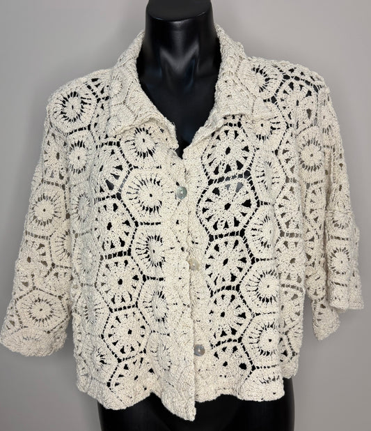 Crocheted beige cardigan on a mannequin against a gray background