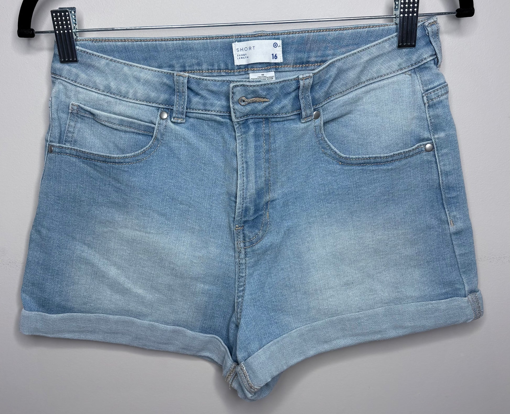 Blue denim shorts on a hanger against a gray background