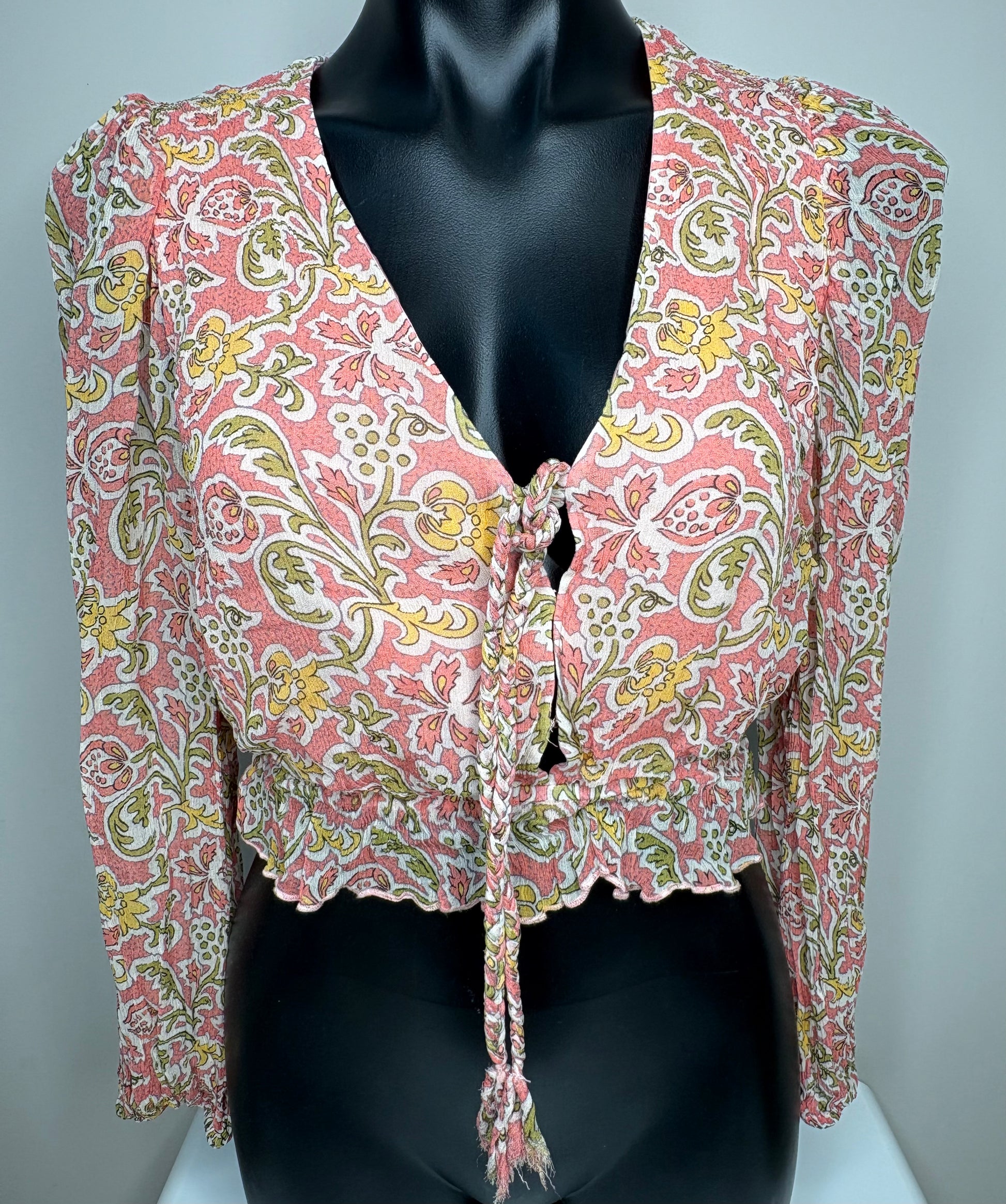 Floral patterned gathered top on a mannequin against a gray background