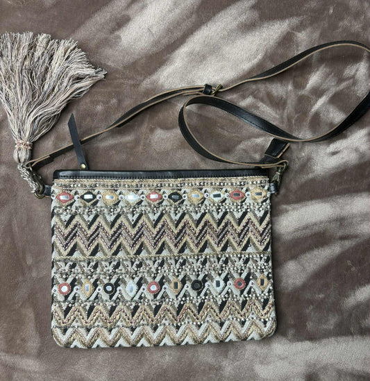 Embroidered handbag with a tassel on a textured brown surface